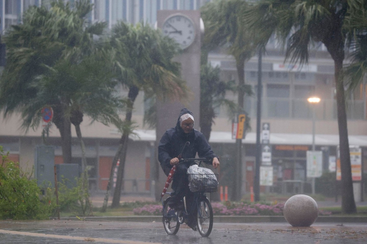 Ein Mann auf einem Fahrrad bahnt sich seinen Weg durch den Regen in Miyazaki.