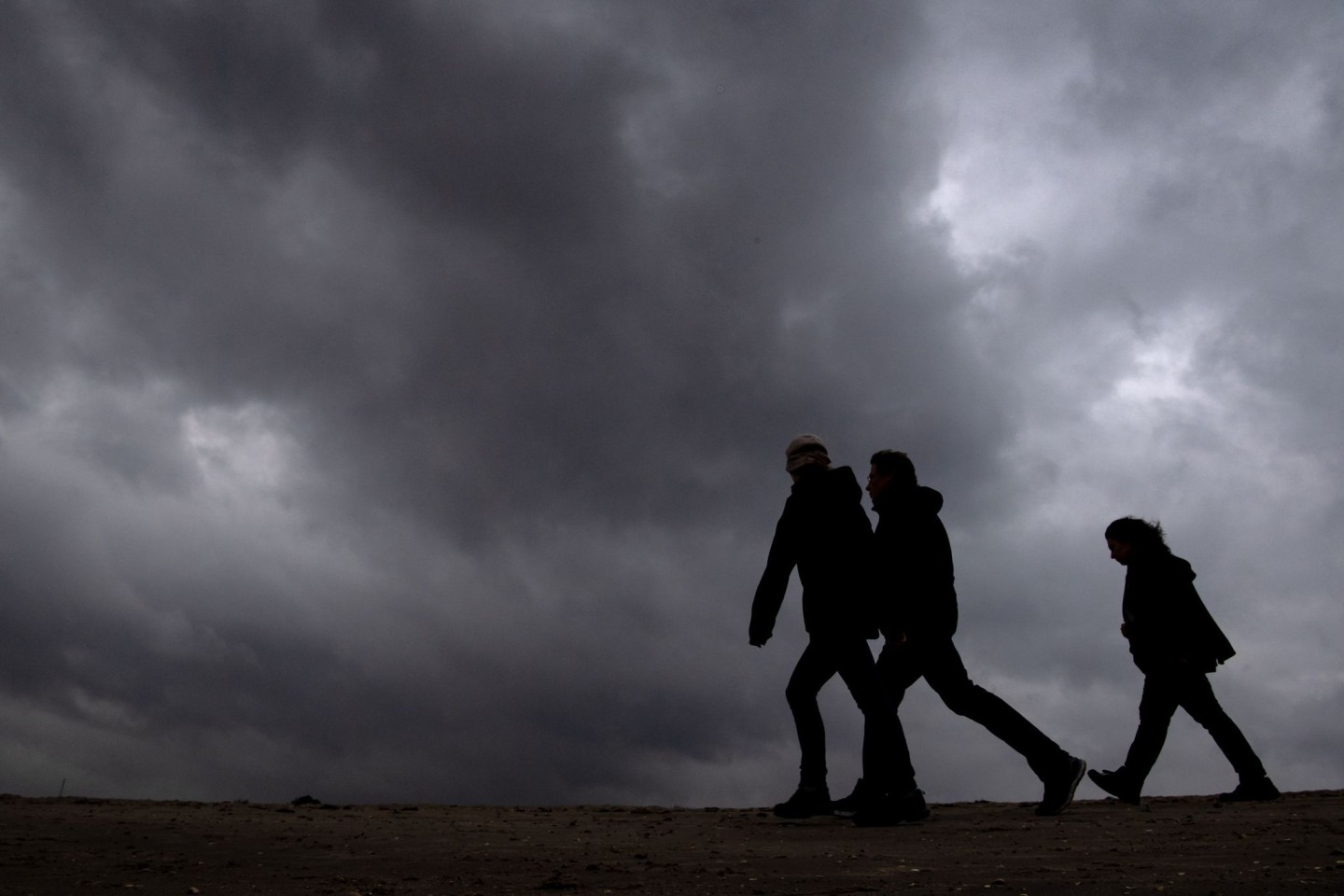 Strand-Spaziergänger unter dunklen Wolken.