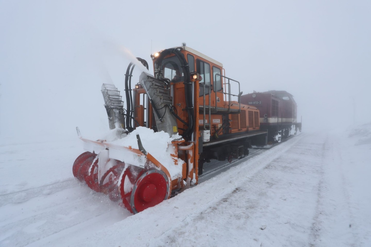Eine Schneefräse der Harzer Schmalspurbahn räumt bei nebligem Wetter den Schnee aus den Gleisen auf dem Brocken.