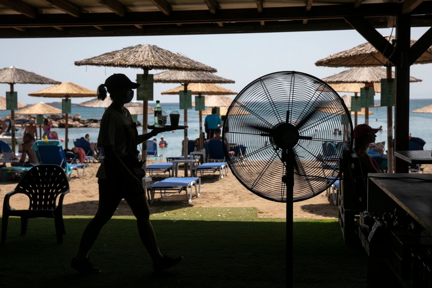 Eine Kellnerin serviert Erfrischungen in einer Strandbar in Griechenland.