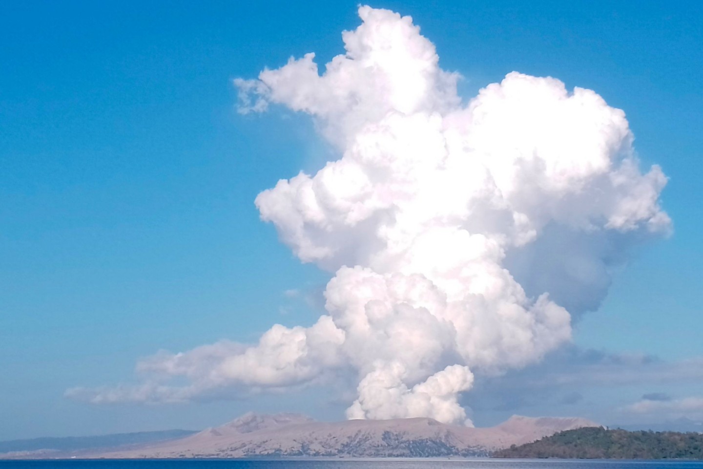 Der Vulkan Taal spuckt weißen Dampf und Asche.