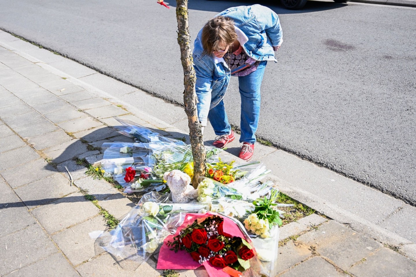 Eine Frau legt Blumen an der Unfallstelle nieder.
