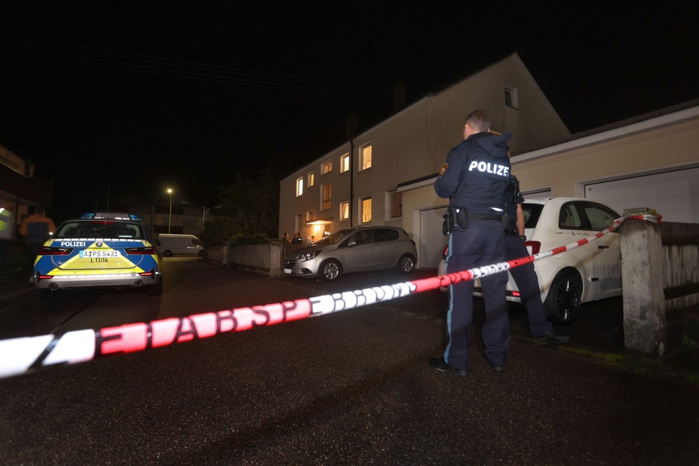 Polizisten am Tatort vor dem Haus in Langweid, in dem drei Menschen erschossen wurden.