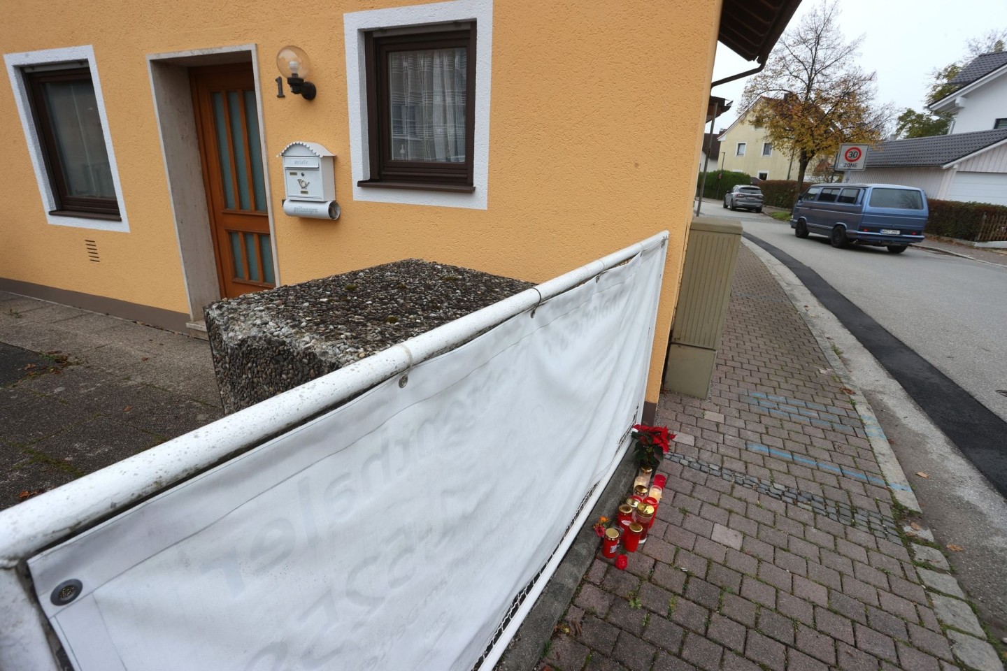 Kerzen und Blumen stehen vor dem Haus in Weilheim, in dem die getöteten Schwestern entdeckt wurden.