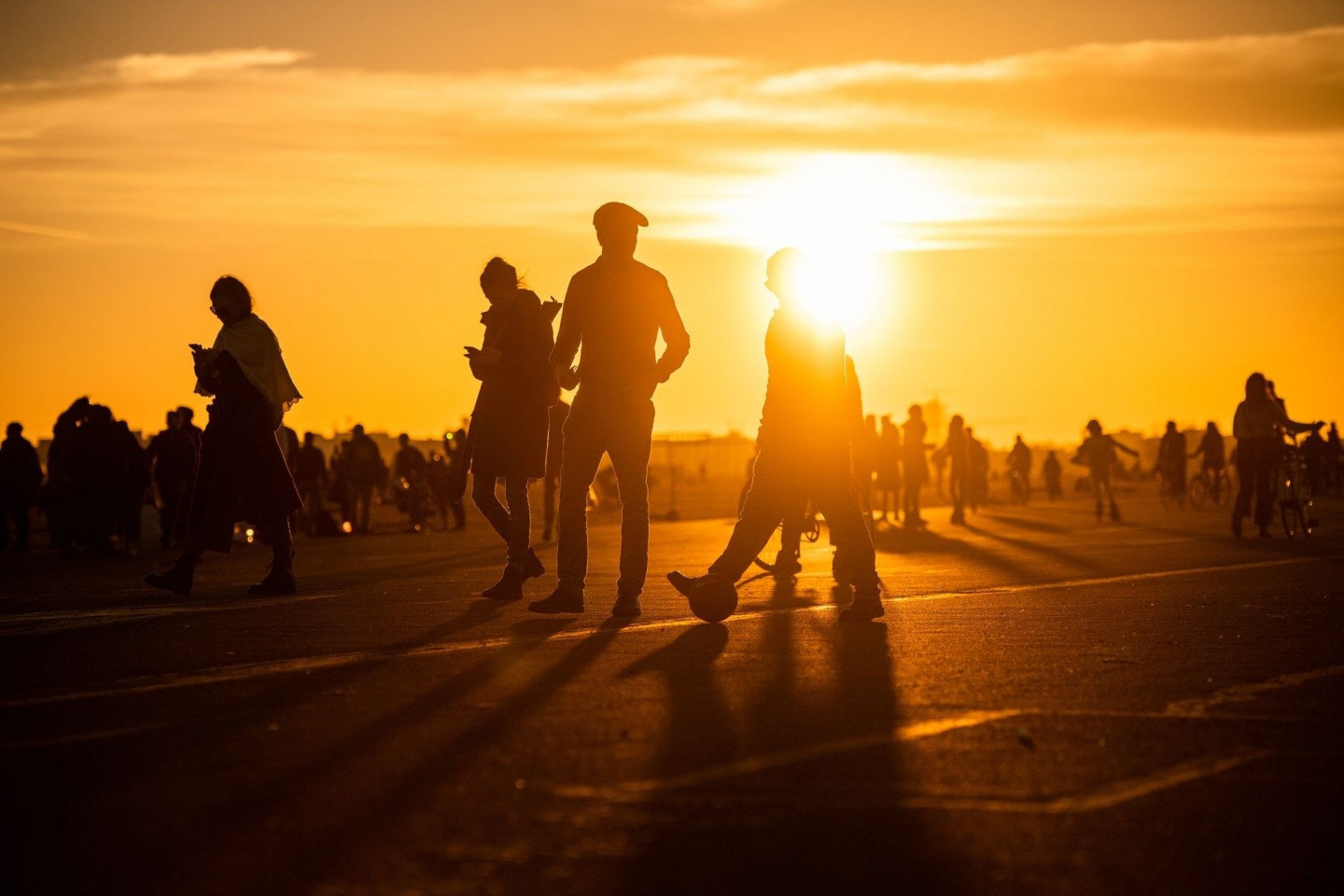 Menschen spazieren während des Sonnenuntergangs bei frühlingshaften Temperaturen auf dem Tempelhofer Feld in Berlin.