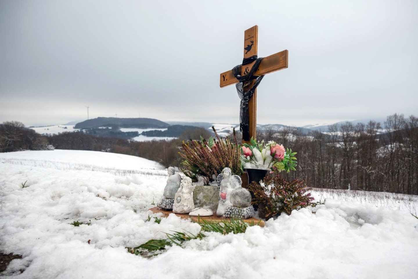 Ein Holzkreuz, Engelsfiguren und Blumen erinnern bei Kusel an die zwei Polizisten, die vor einem Jahr im Dienst getötet wurden.