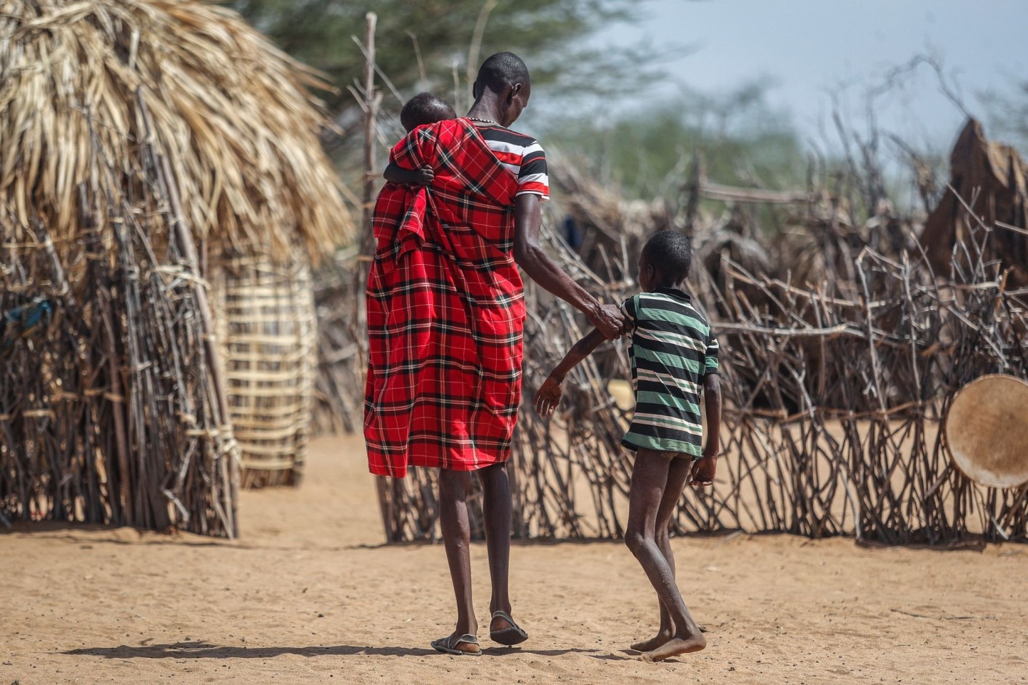 Ein Vater hilft seinem unterernährten Sohn beim Gehen in der Nähe ihrer Hütte in dem Dorf Lomoputh im Norden Kenias.
