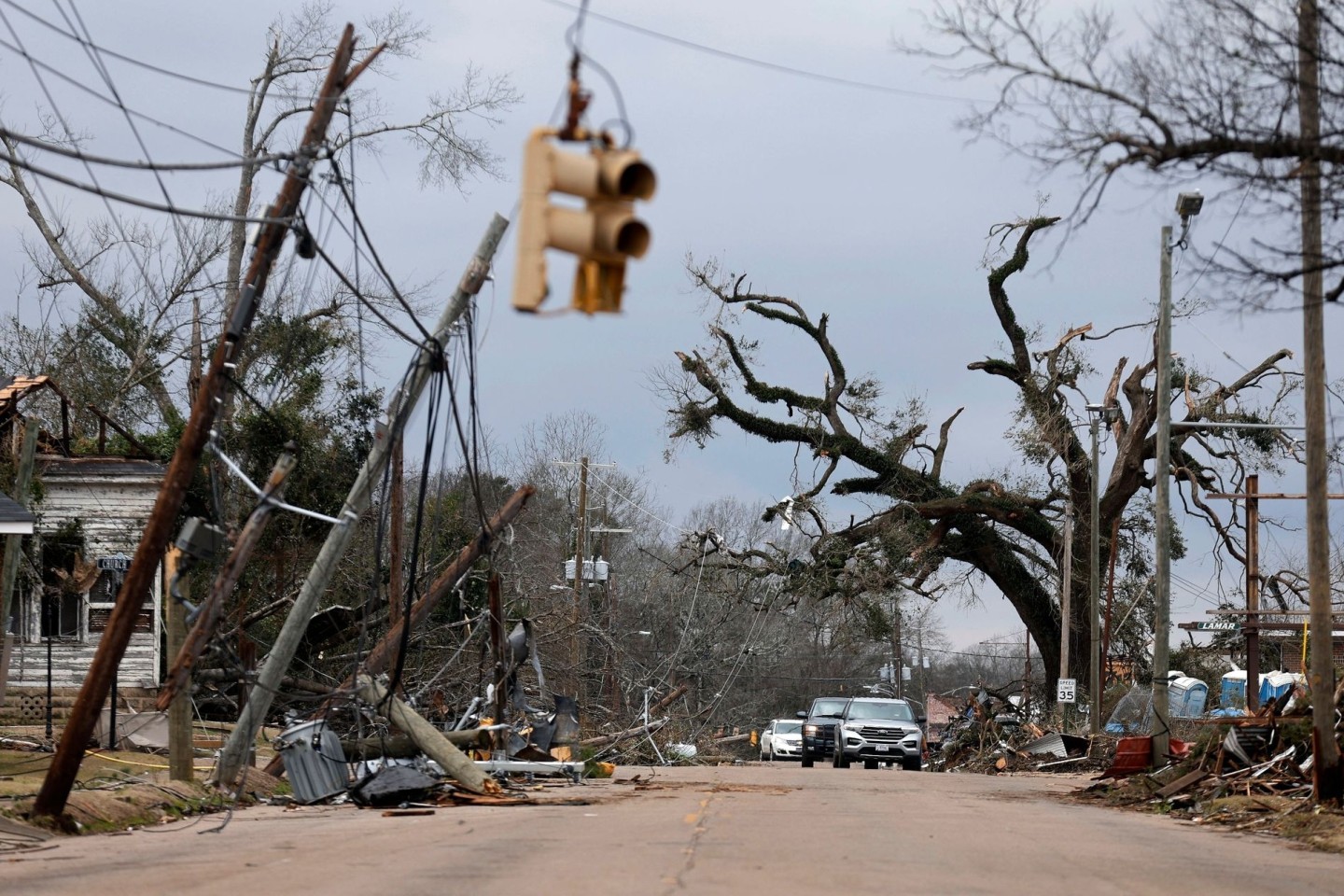 Autos fahren vorsichtig an umgestürzten Bäumen und Stromleitungen in Selma vorbei.