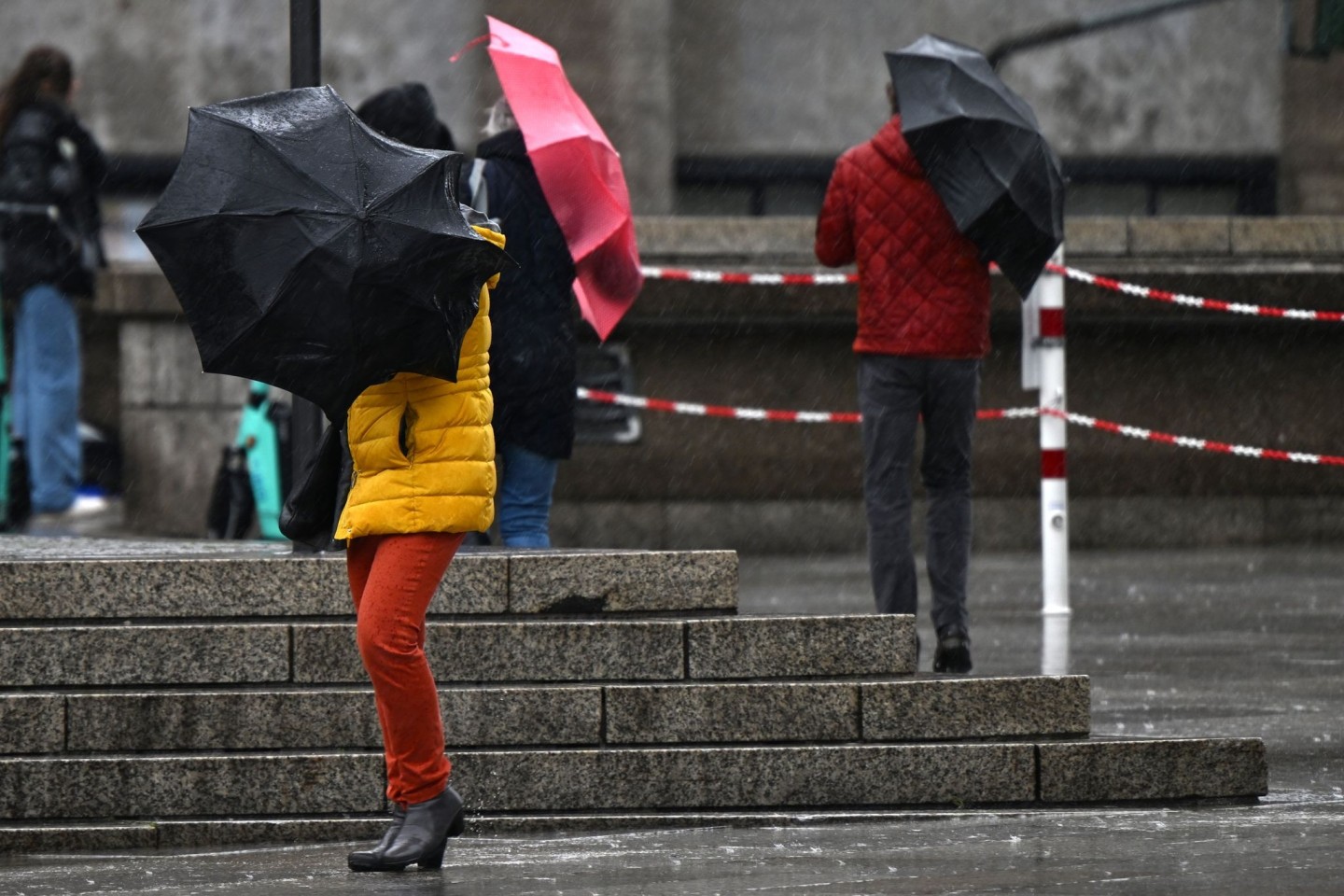 Passanten kämpfen in Köln mit dem Wind und ihren Regenschirmen. Zum Wochenbeginn ist das Wetter in Nordrhein-Westfalen weiter stürmisch und regnerisch.
