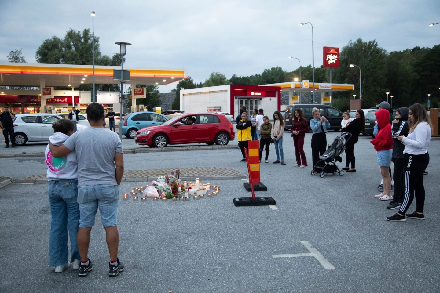 Menschen stehen neben Blumen und Kerzen auf einen Parkplatz, wo die zwölfjährige Adriana aus einem vorbeifahrenden Auto heraus erschossen wurde (Archivbild).